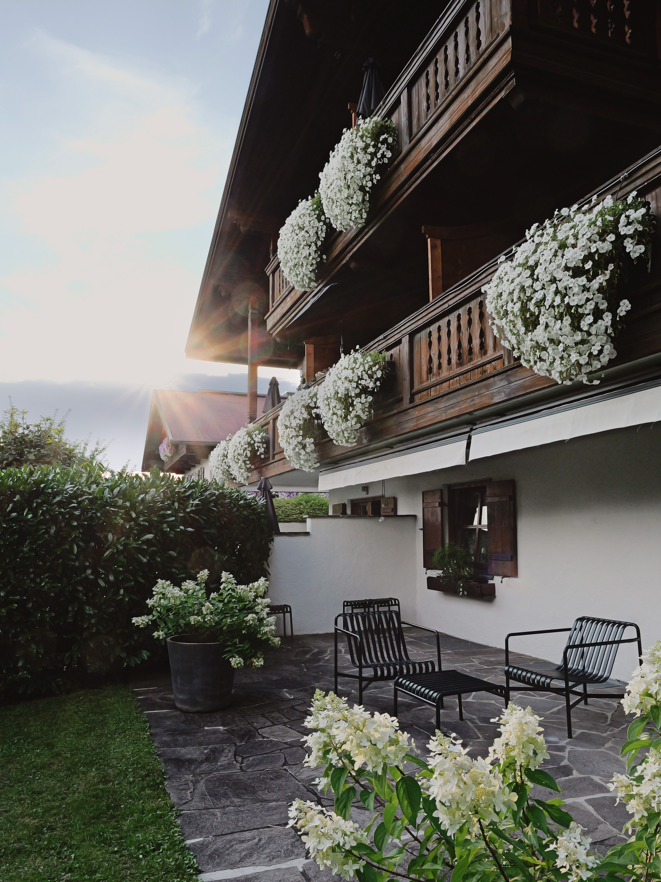 Alpenchalet Reit im Winkl mit bepflanzten Balkonen und Gartenhecke